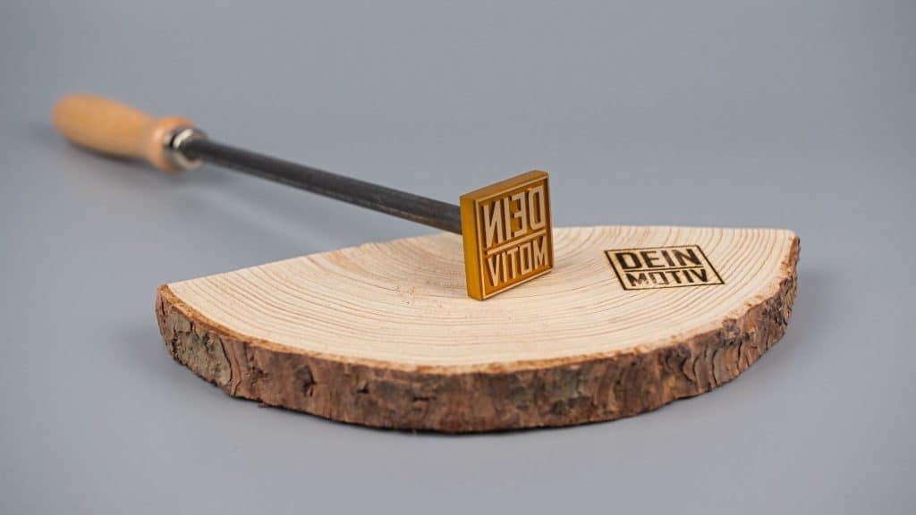 Brennstempel mit dem Motiv "Dein Motiv" auf einer Holzscheibe eines Baums