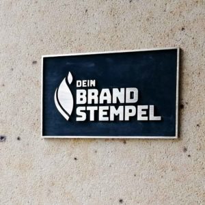 Hier ist ein Messingschild zu sehen, das schwarz patiniert wurde.