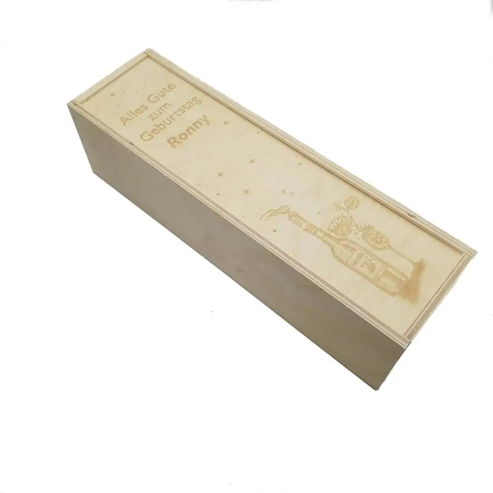 Eine helle Weinkiste mit Holzwolle Füllung. Schließen lässt sie sich mit einer Schubfachfunktion. Eine praktische Verpackung zum Verschenken von Weinflaschen. Mit einem schönem Motiv mit einer Weinflasche auf der eine Kerze steckt deren Docht brennt. Direkt rechts daneben ein bauchiges Weinglas in das eine Weinrebe mit Blättern drapiert wurde. Während die Früchte im Glas verschwinden räkeln sich die Weinblätter gen Himmel. Das Motiv wurde gezeichnet und anschließend in das Holz gelasert. Über dem Motiv ist ein Schriftzug : „alles Gute zum Geburtstag Ronny“. Dieser ist optional anpassbar. Seitlich