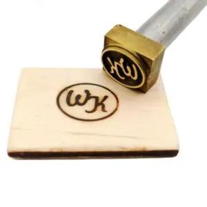 Brennstempel mit Initialen W und K, Brandmotiv auf kleines Stück Holz