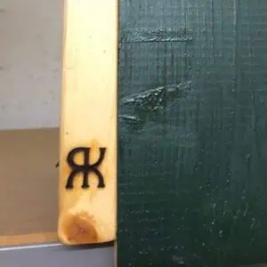 Das Bild zeigt ein auf Holz aufgebrachtes Brandzeichen.