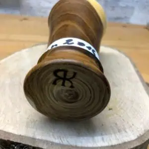 Das Foto zeigt einen Holzgegenstand, auf den Initialen eingebrannt wurden.