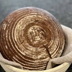 Das Foto zeigt dunkles, rundes Brot in einem Tuch.