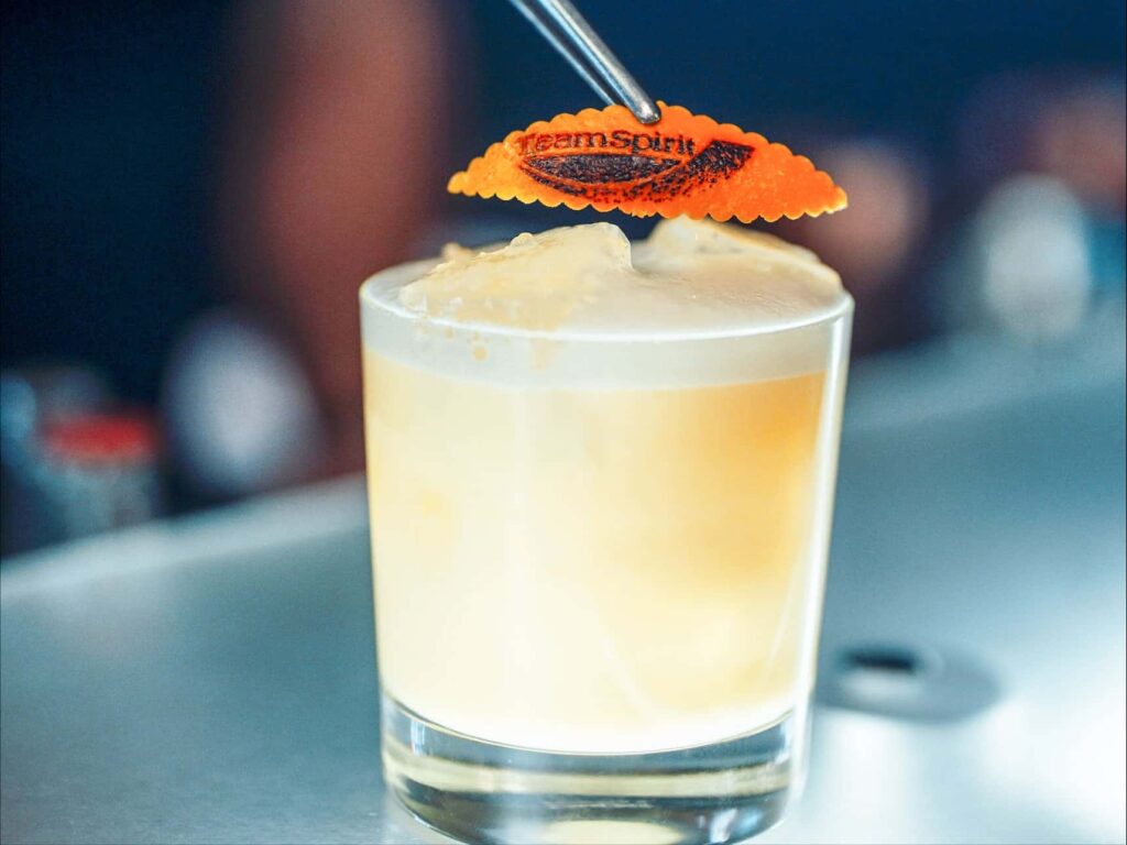 Das Foto zeigt ein kleines Cocktailglas mit gebrandeter Orangenschale