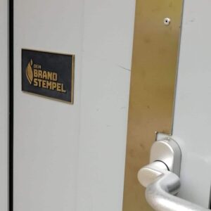 Das Bild zeigt ein Türschild aus Messing.